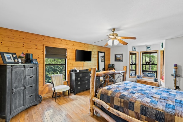 bedroom featuring wooden walls, ceiling fan, and light wood-type flooring