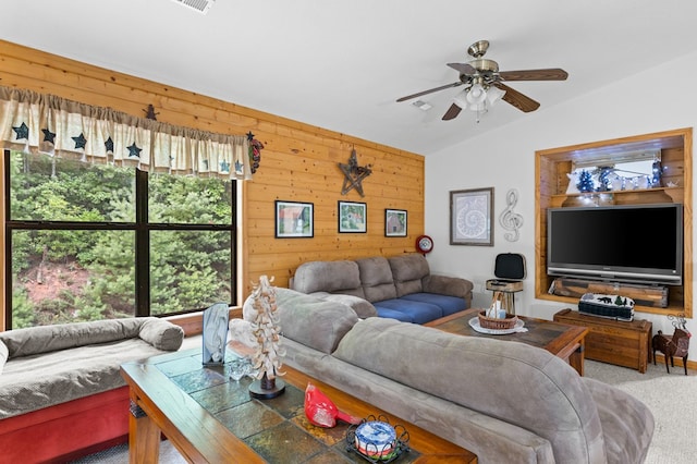 living room featuring ceiling fan, lofted ceiling, carpet floors, and wooden walls