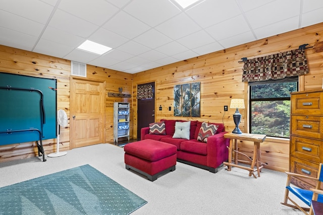 living room with carpet, a drop ceiling, and wooden walls