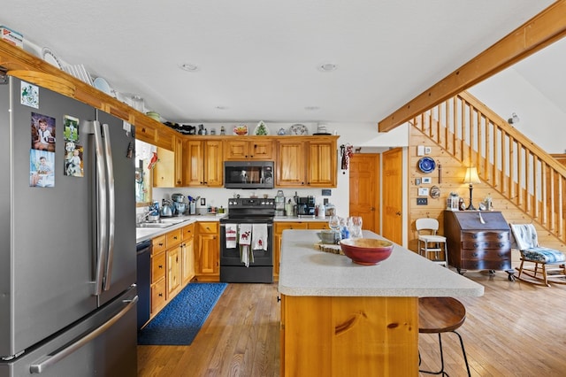 kitchen featuring a kitchen breakfast bar, light hardwood / wood-style floors, a kitchen island, and black appliances