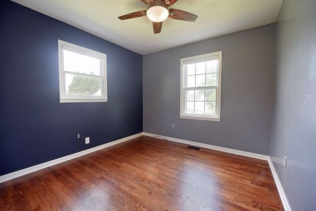 spare room featuring ceiling fan, hardwood / wood-style floors, and a wealth of natural light