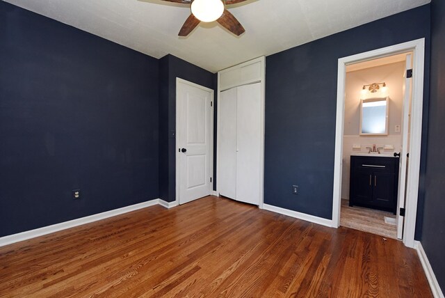 unfurnished bedroom with ceiling fan, connected bathroom, dark hardwood / wood-style flooring, and a closet