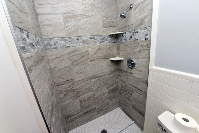 bathroom with tiled shower and tile walls