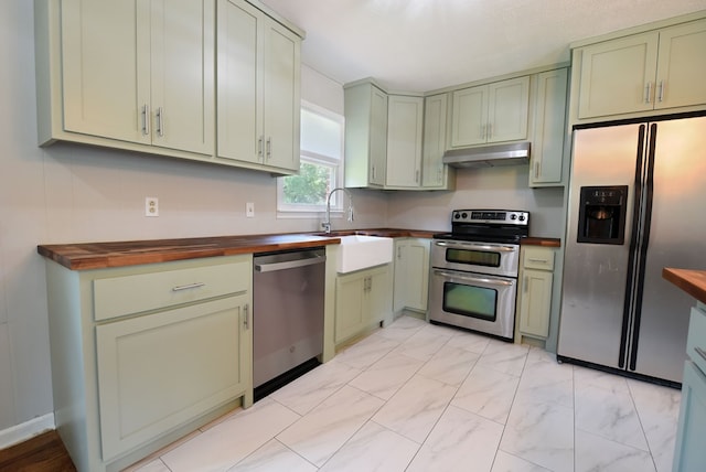 kitchen with stainless steel appliances, sink, wooden counters, and green cabinetry