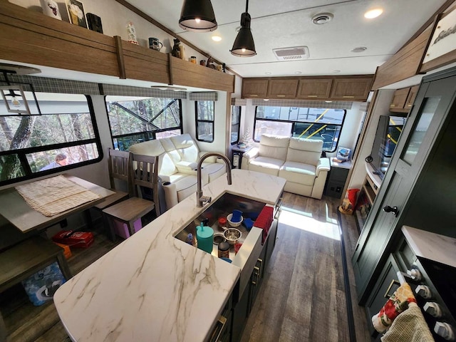 kitchen featuring visible vents, lofted ceiling, a sunroom, dark wood-style flooring, and decorative light fixtures