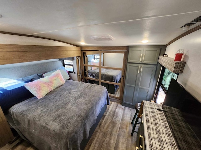 bedroom featuring wood finished floors, visible vents, and crown molding