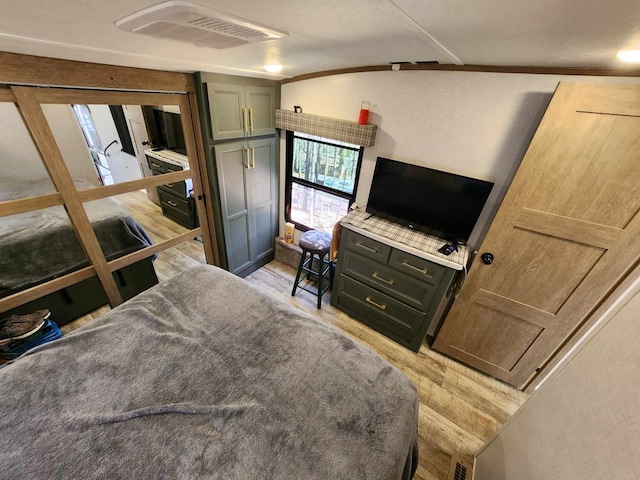 bedroom with light wood finished floors, visible vents, and crown molding