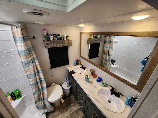 full bath featuring double vanity, toilet, wood finished floors, shower / bathtub combination with curtain, and a sink