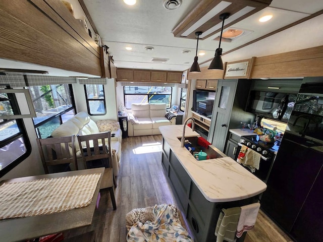 kitchen with a center island with sink, visible vents, dark wood-style floors, black appliances, and recessed lighting