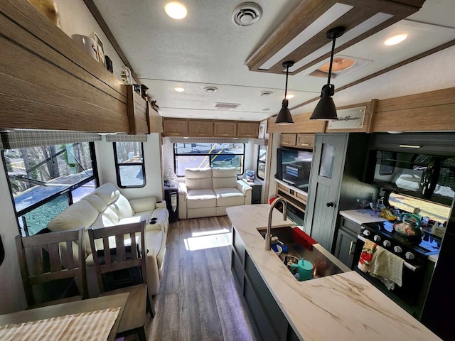 kitchen with dark wood-type flooring, visible vents, wood walls, and light stone countertops