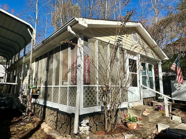 view of side of property with a sunroom and a carport