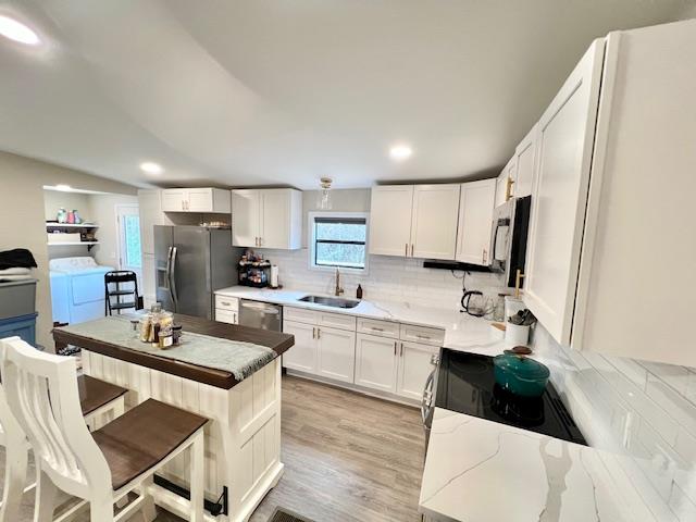 kitchen with white cabinetry, washer and clothes dryer, sink, and appliances with stainless steel finishes