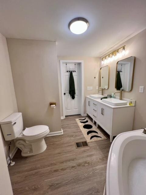 bathroom with hardwood / wood-style floors, vanity, and toilet