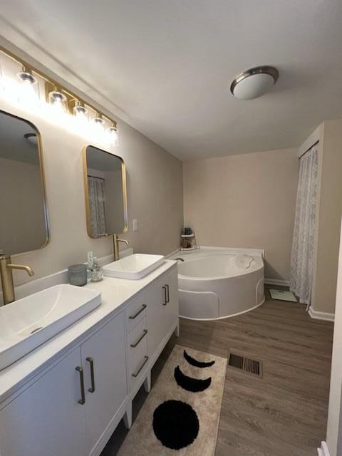 bathroom featuring hardwood / wood-style floors, vanity, and a tub to relax in