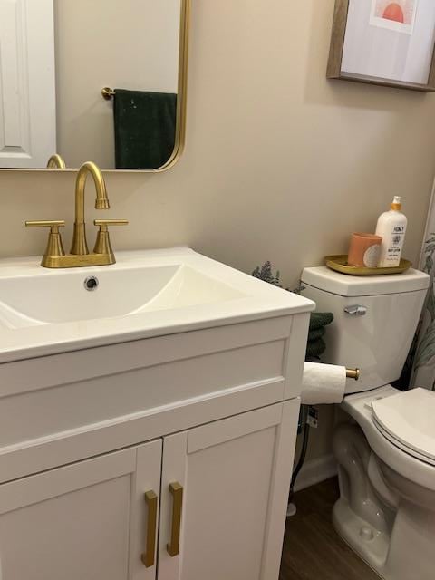 bathroom with hardwood / wood-style floors, vanity, and toilet