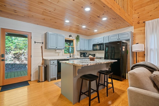 kitchen with black appliances, a center island, sink, and light hardwood / wood-style flooring