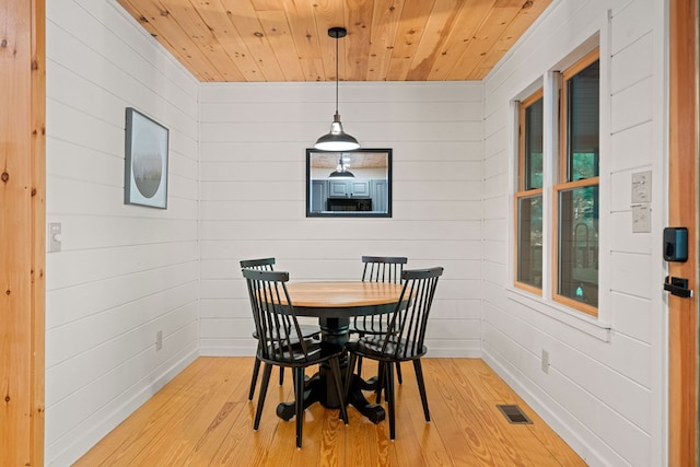 dining area featuring wood walls, wood ceiling, and light hardwood / wood-style flooring