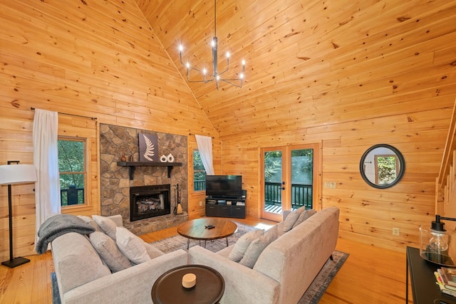 living room featuring a fireplace, high vaulted ceiling, plenty of natural light, and wood walls