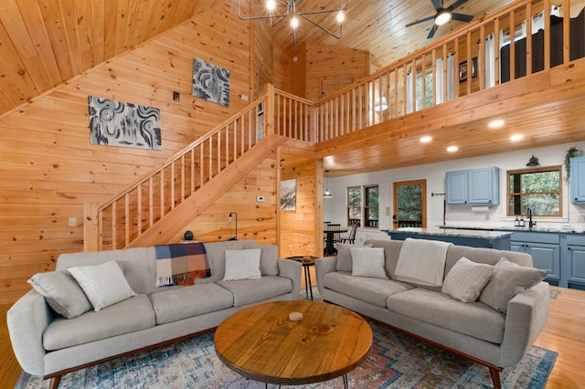 living room featuring sink, wooden ceiling, light hardwood / wood-style flooring, high vaulted ceiling, and wood walls