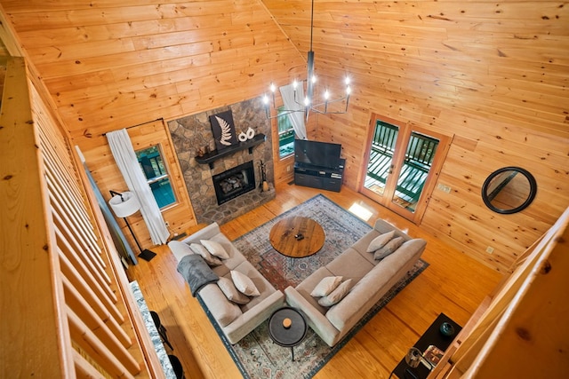 unfurnished living room featuring wood walls, a fireplace, high vaulted ceiling, and a chandelier