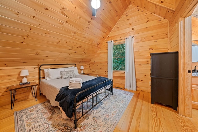 bedroom featuring wooden walls, light hardwood / wood-style floors, and lofted ceiling