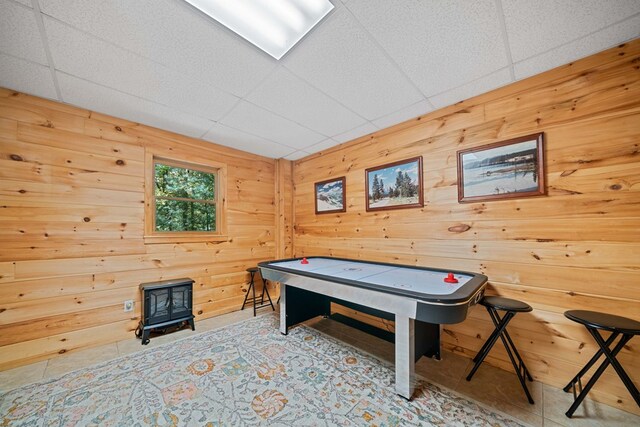 game room with wooden walls and a drop ceiling