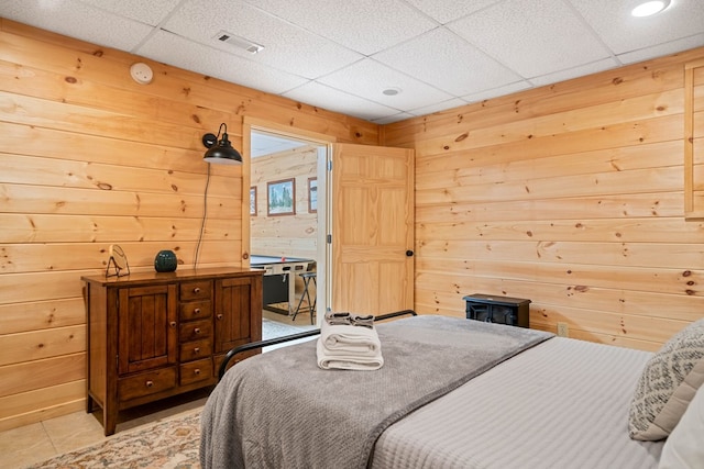 tiled bedroom featuring a paneled ceiling and wooden walls