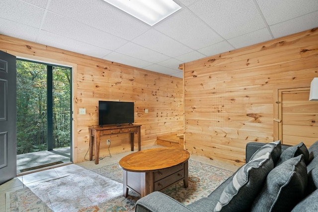 living room with a drop ceiling and wooden walls