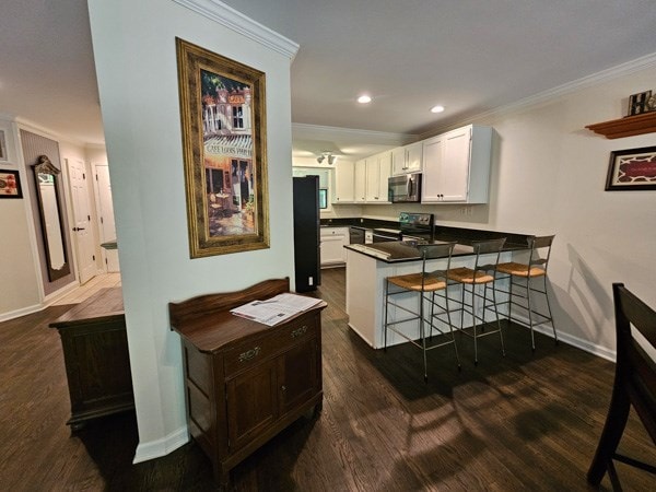 kitchen featuring appliances with stainless steel finishes, ornamental molding, baseboards, and a peninsula