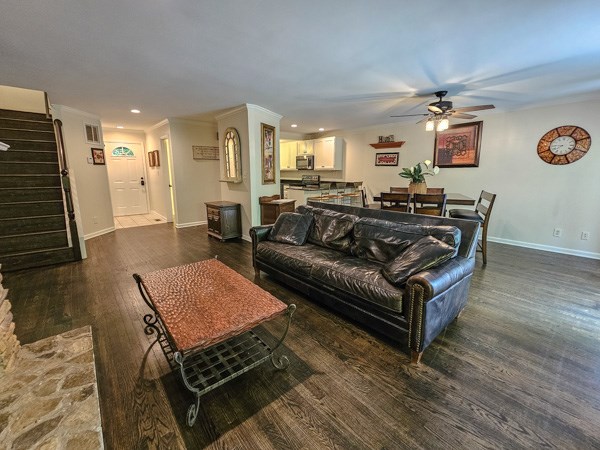 living area with baseboards, a ceiling fan, stairs, and wood finished floors