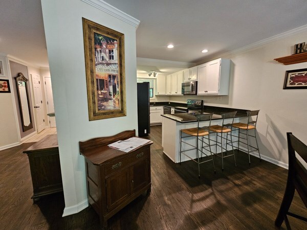 kitchen featuring appliances with stainless steel finishes, ornamental molding, baseboards, and a peninsula