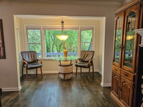 sitting room with baseboards, plenty of natural light, ornamental molding, and dark wood-type flooring