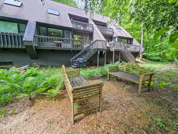 back of house featuring a deck, a shingled roof, and stairs