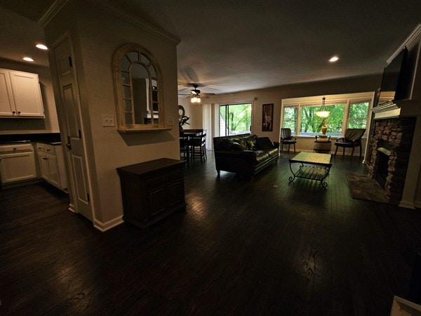 living room featuring a ceiling fan, recessed lighting, a stone fireplace, and dark wood-type flooring