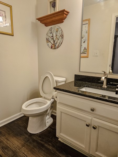 bathroom with toilet, baseboards, wood finished floors, and vanity