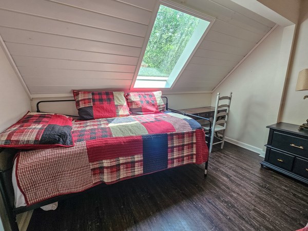 bedroom featuring baseboards, wood finished floors, and lofted ceiling