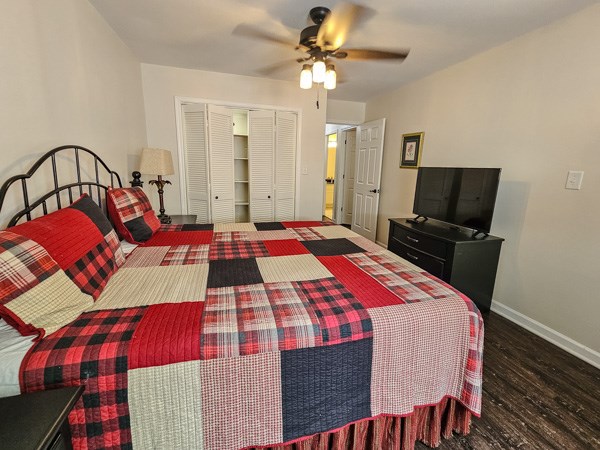 bedroom with a ceiling fan, baseboards, wood finished floors, and a closet