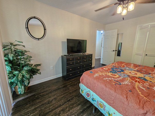 bedroom with a ceiling fan, baseboards, dark wood finished floors, and a closet