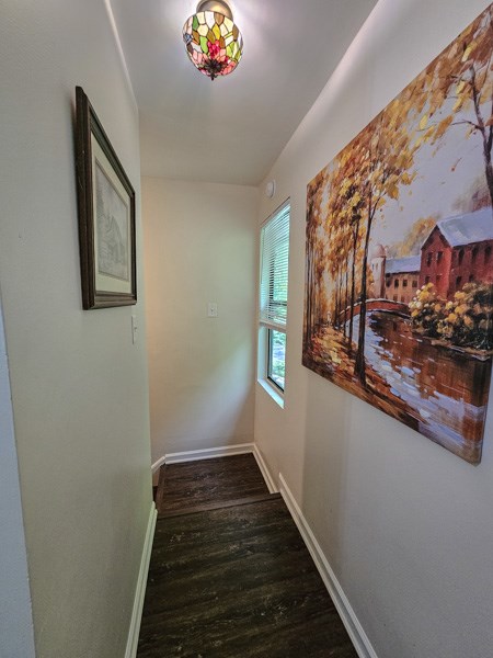 corridor featuring baseboards and wood finished floors