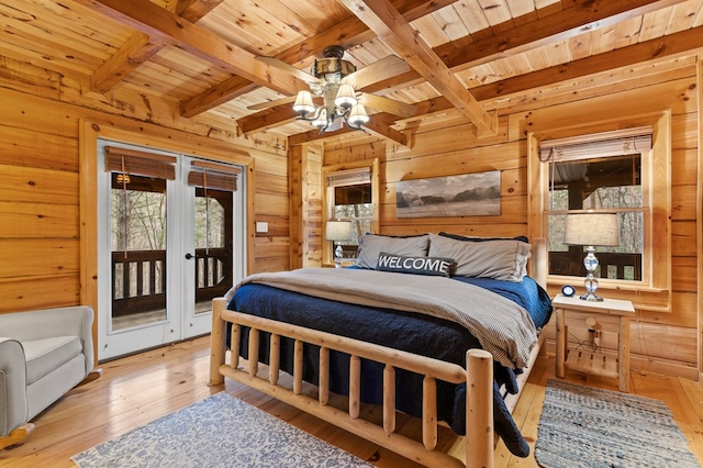 bedroom with access to outside, beamed ceiling, light wood-type flooring, and wood walls