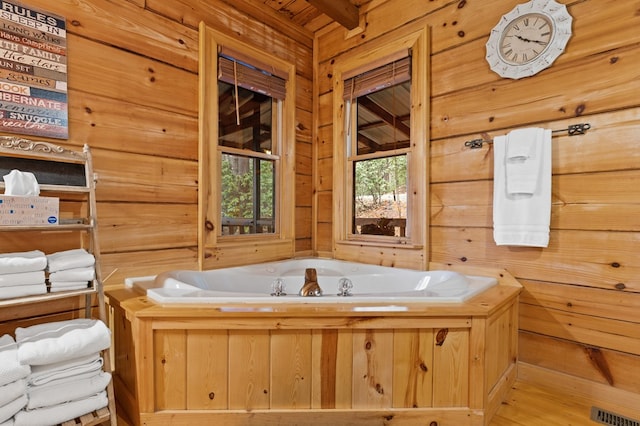 full bath with visible vents, a garden tub, and wood walls