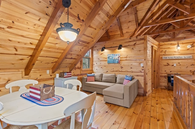 dining area featuring light wood-style floors, wood ceiling, wood walls, and vaulted ceiling with beams