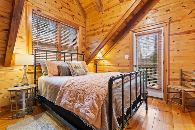 bedroom featuring access to outside, wood walls, hardwood / wood-style flooring, and vaulted ceiling