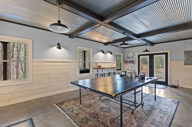 playroom with wooden walls, finished concrete floors, beamed ceiling, wainscoting, and french doors