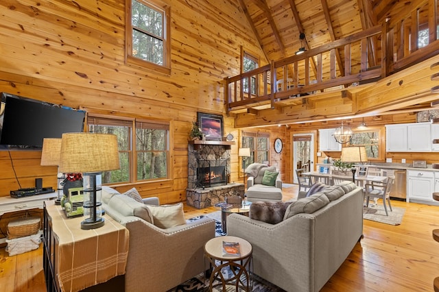 living room with wooden walls, wood ceiling, light wood-type flooring, a fireplace, and high vaulted ceiling