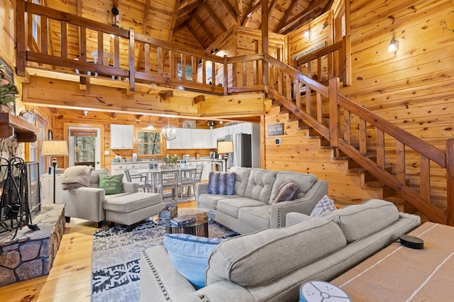 living room with a fireplace, stairs, wood ceiling, wood walls, and light wood-type flooring