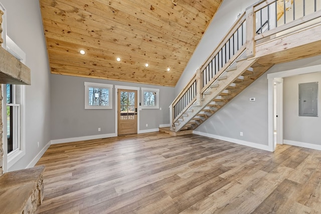 interior space with high vaulted ceiling, wood finished floors, electric panel, and baseboards