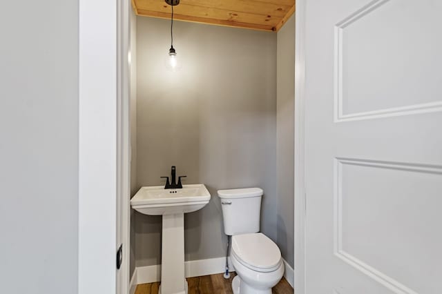 bathroom featuring toilet, a sink, baseboards, and wood finished floors