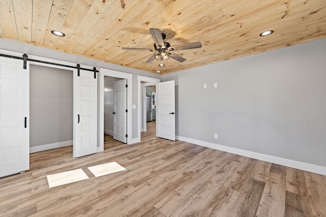 unfurnished bedroom with recessed lighting, a barn door, light wood-type flooring, wooden ceiling, and baseboards