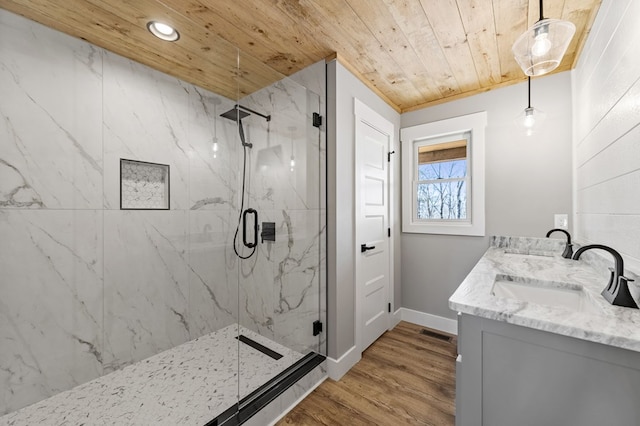 bathroom featuring wood finished floors, wooden ceiling, a sink, and a marble finish shower